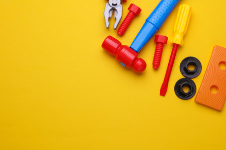 Set of children's toy tools on a yellow background. Flat lay