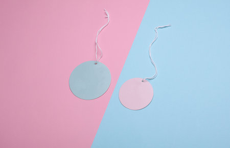 Round blue and pink price tags on ropes, pastel background