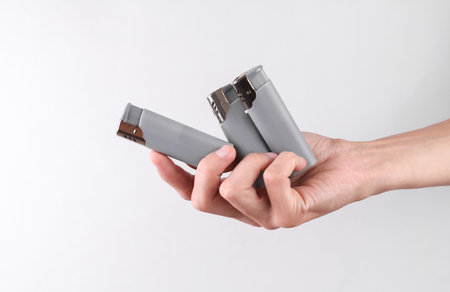 Female hand holding a lighters on gray background