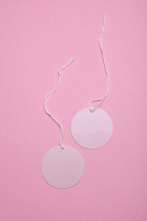 Round pink tags on ropes, pastel background