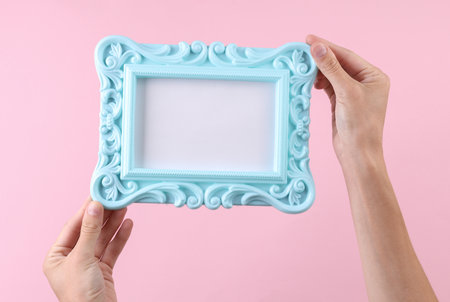 Hands holding white blank Ornamental photo frame on pink background