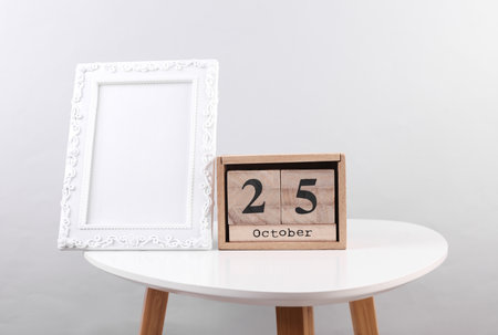 Wooden calendar organizer with date October 25 and photo frame on table