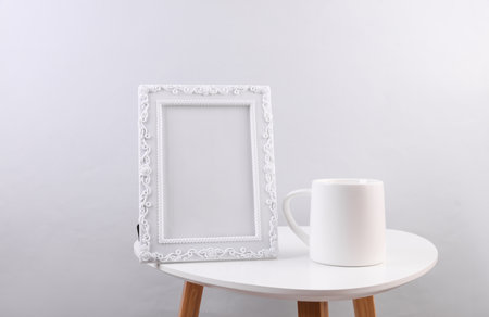 White coffee cup and picture frame on white table against white wall.の写真素材