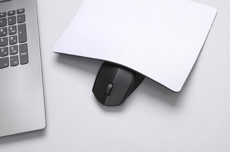 Mockup of white blank computer mouse pad with props, mouse and laptop on gray background. Top view....