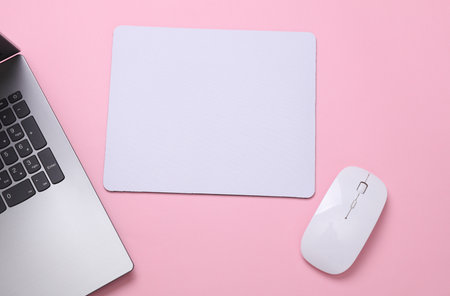 Mockup of white blank computer mouse pad with props, mouse and laptop, pink background. Top view....