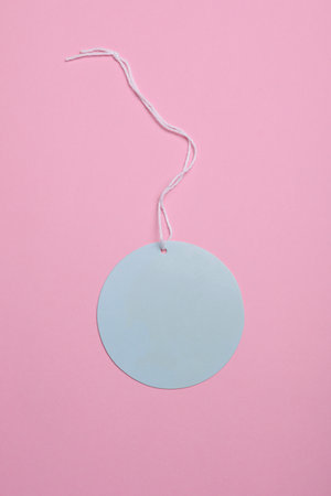 Round blue price tag on rope, pink pastel background