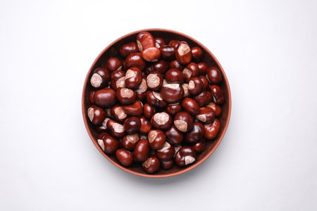 Lots of chestnuts in a bowl on white background. Top viewの写真素材