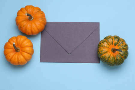 Miniature natural pumpkins with envelope on blue background. Autumn still life. Halloween theme. Top view. Copy spaceの写真素材