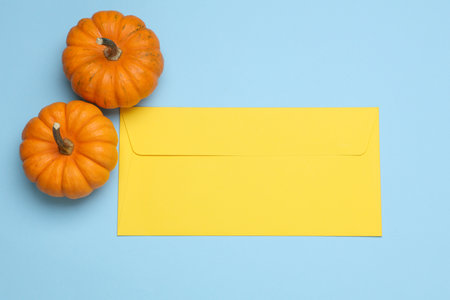 Miniature natural pumpkins with envelope on blue background. Autumn still life. Halloween theme. Top view. Copy spaceの写真素材