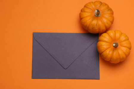 Two pumpkins and an envelope on a orange background, top viewの写真素材