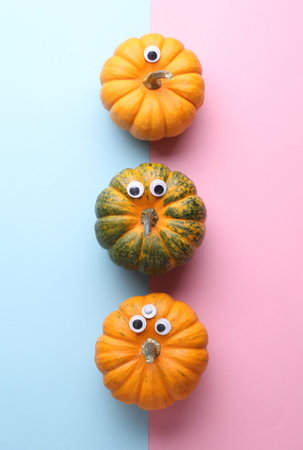 Pumpkins with googly eyes on a pink blue background. Halloween decor, handmade for holiday, 31 October. Top viewの写真素材