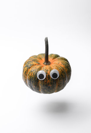 Pumpkin with googly eyes floating on white background. Halloween decor, handmade for holiday, 31 October. Top viewの写真素材