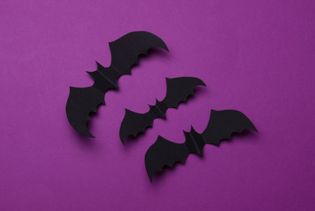 Paper cut black bats on purple background. Halloween decor. Copy space