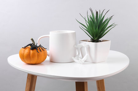 White ceramic cup and halloween decor on table. Mockup for designの写真素材