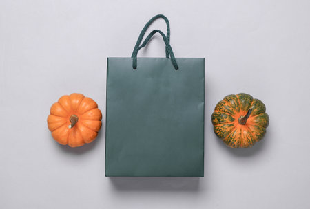 Green cardboard bag and pumpkins on gray background. Autumn discountsの写真素材