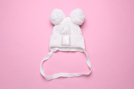 Children's warm hat with a balabons on a pink background