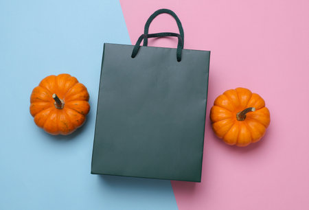 Green cardboard bag and pumpkins on pink blue background. Autumn discountsの写真素材