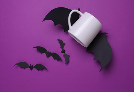 White ceramic cup mockup for your design and Halloween decorative bats on purple background