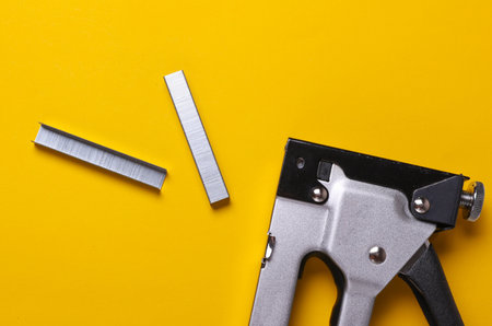 Construction stapler with staples on a yellow backgroundの写真素材