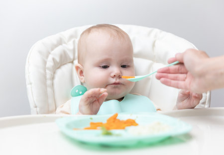 Mom feeds baby with a spoonの写真素材