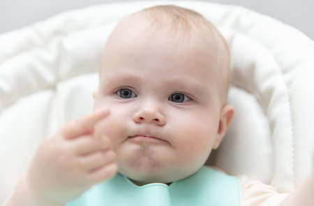 Cute baby eating food at feeding table