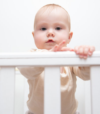 Portrait of a cute baby in a crib with bumpers