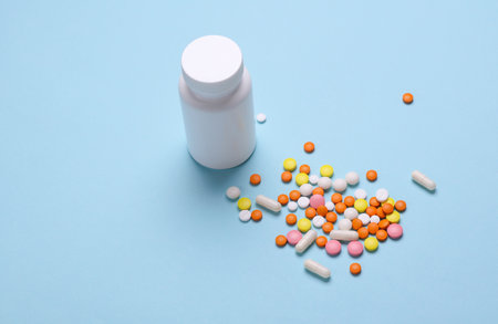 White plastic bottle with pills on blue background. Medicine concept. Mockup for design. Top view