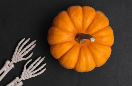 Pumpkin and skeleton hands on black background. Halloween decorの写真素材