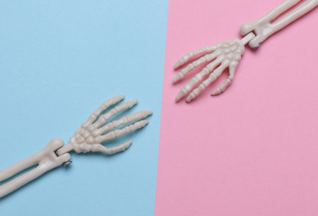 Decorative skeleton hands on purple background. Halloween still life. Top view