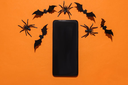 Smartphone with halloween bats and spiders on orange backgroundの写真素材