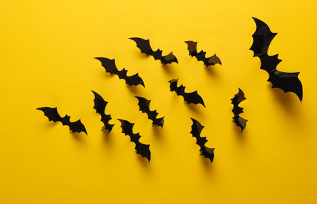 Halloween decoration concept. Black paper bats flying on yellow background. Top viewの写真素材