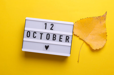 12 October letterboard text on LED Lightbox with autumn fallen leaves, yellow background. Seasonal...