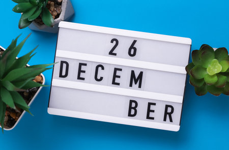 Lightbox with text December 26 on blue backgroung with decorative plant. Flat lay. Top viewの写真素材
