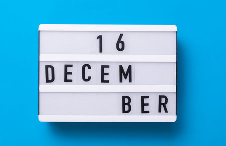 Lightbox with text December 06 on blue backgroung with decorative plant. Flat lay. Top viewの写真素材