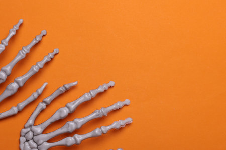 Halloween decoration concept. Plastic skeleton hands on orange backgroundの写真素材