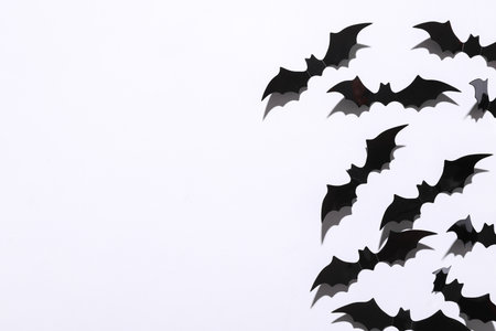 Halloween decoration concept. Black paper bats flying on white background. Top view