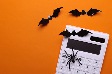 White calculator with halloween decor on orange backgroundの写真素材