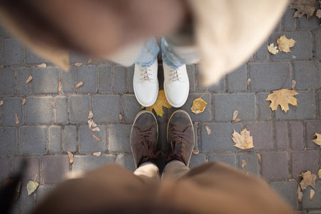 Top view of feet in shoes of a couple in love among autumn fallen leavesの写真素材