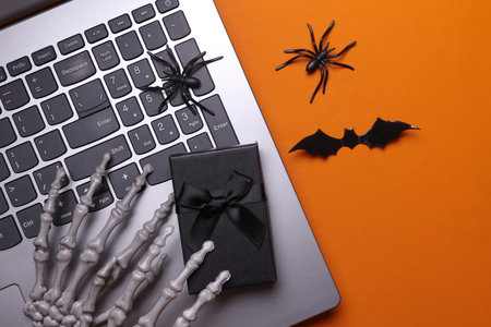 Online shopping for gifts, halloween concept. Skeleton hands using laptop, gift box and holiday...