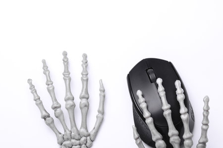 Halloween decoration concept. Plastic skeleton hand holding pc mouse on white backgroundの写真素材