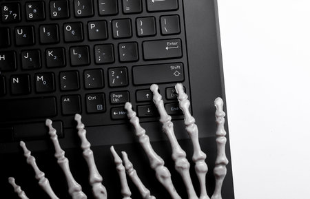 Skeleton hands typing on laptop keyboard. Deadline, business conceptの写真素材