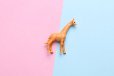 Plastic toy giraffe figurine on blue pink backgroundの写真素材