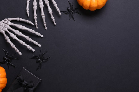 Halloween decoration concept. Plastic skeleton hands and decor on black background. Flat lay. Copy spaceの写真素材