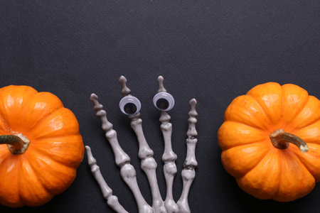 Halloween decoration concept. Plastic skeleton hands and decor on black background. Flat lay.の写真素材