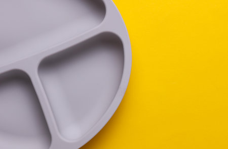 Silicone plate with dividers for feeding baby on yellow backgroundの写真素材