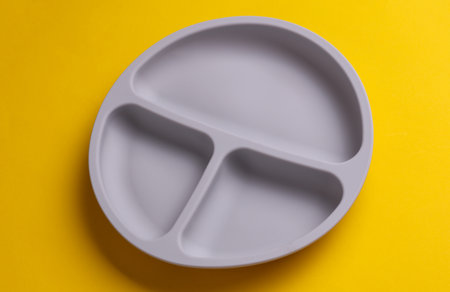 Silicone plate with dividers for feeding baby on yellow backgroundの写真素材
