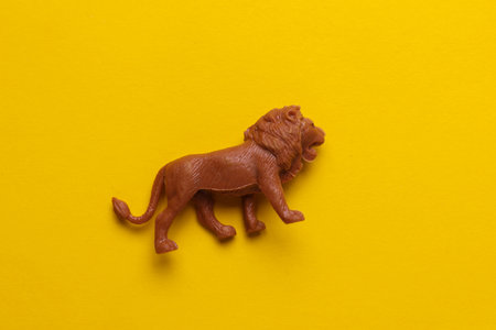 Plastic toy lion figurine on yellow backgroundの写真素材