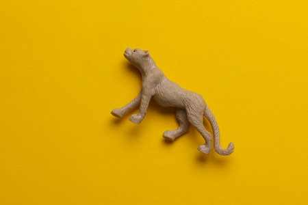 Plastic toy cheetah figurine on yellow backgroundの写真素材