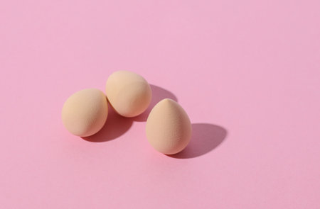 Eggs makeup sponges blender on pink background. Creative layout. Minimalism creative beauty still...