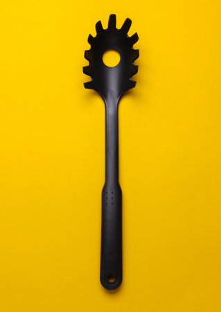 Black plastic kitchen tool on yellow backgroundの写真素材